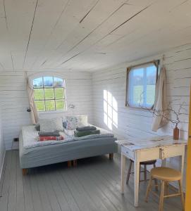 a room with a bed and a table and windows at Röda Vagnen Nostalgi och natur i unik cirkusvagn in Hörby