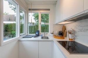 a white kitchen with a sink and a window at Welcome in - Vakantiewoning met zonnige tuin, dichtbij zee en strand I Noordendolfer 2-49 in Zoutelande +50 photos