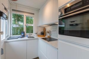 a white kitchen with a sink and a microwave at Welcome in - Vakantiewoning met zonnige tuin, dichtbij zee en strand I Noordendolfer 2-49 in Zoutelande