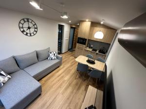 a living room with a couch and a table and a clock at Domek Przy Jeziorze in Kujanki
