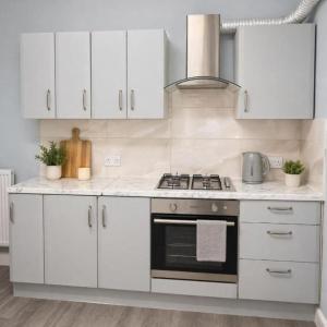 a white kitchen with a stove and white cabinets at The Range Nestled Nook in Manchester