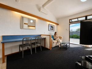 a woman sitting on a couch in a living room at Teal Motor Lodge in Gisborne