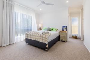 a white bedroom with a bed and a window at 10 Beach Houses in Agnes Water