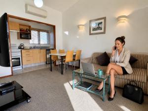 a woman sitting on a couch talking on a cell phone at Teal Motor Lodge in Gisborne