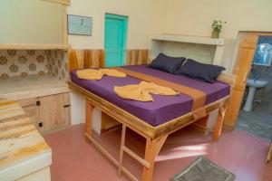 a bedroom with a bed with purple sheets and a bathroom at Dreamy Hostel Arugambay in Arugam Bay