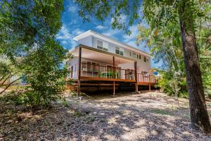 a house with a wrap around deck in the woods at 10 Beach Houses in Agnes Water
