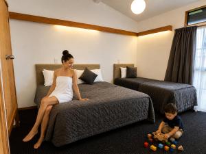 a woman sitting on a bed next to a child in a hotel room at Teal Motor Lodge in Gisborne +24 photos