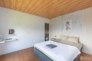 a bedroom with a white bed and a wooden ceiling at Fortune Glamping in Diyeng +8 photos