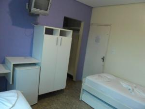 FlorianoComodoro Hotel e Churrascaria的小房间设有白色橱柜和电视