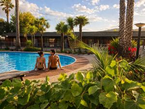 two people sitting by the pool at a resort at Teal Motor Lodge in Gisborne