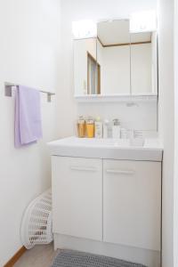 a white bathroom with a sink and a mirror at ラベンダー富士 富士山と過ごすおしゃれな隠れ家 in Fuji