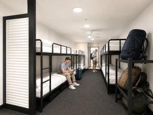 a man sitting on a bed in a room with bunk beds at London Gate Backpackers Hostel in Sydney +73 photos