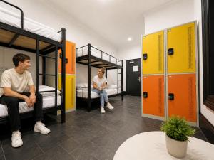 a man and a woman sitting on bunk beds at London Gate Backpackers Hostel in Sydney