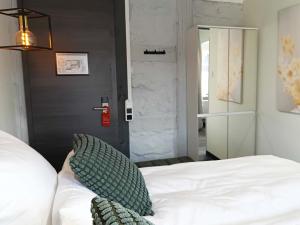 a bedroom with a white bed with a green pillow at NOX HOTEL - Digital-Check-In - No Reception - nahe Bretten & Karlsruhe - 4 Essence in Wössingen