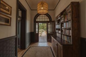 a hallway with a library with book shelves and a chandelier at Waterval Guest Farm in Bloemfontein