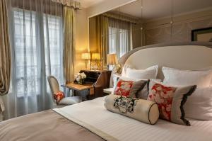 a bedroom with a large bed with a chair and a desk at Hotel Westminster in Paris