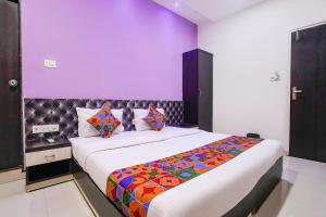 a bedroom with two beds and a purple wall at FabHotel Marvey Residency in Mumbai