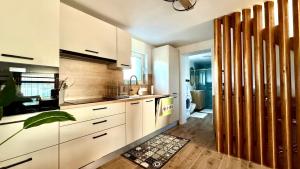 a kitchen with white cabinets and a wooden floor at TJ Nyaraló in Markaz
