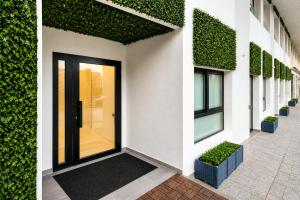 a white building with a black door and green plants at Nova MSuites Valencia in Valencia