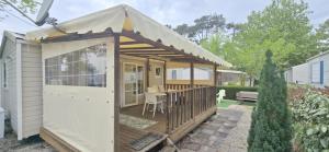 a small house with a deck with a table at Bungalow-Mobilhome - Petit prix- Océan -Forêt -Camping 3 étoiles in Bias