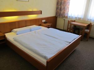 Schlafzimmer mit einem großen Bett, einem Tisch und einem Schreibtisch in der Unterkunft Gasthof zum Galik in Großkrut
