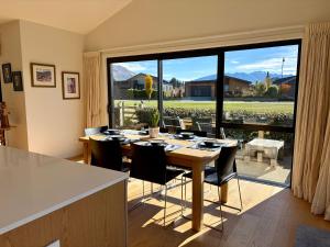 a dining room with a table and a large window at Alpine Abode in Wanaka