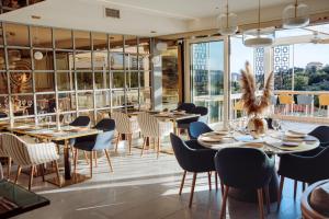 a restaurant with tables and chairs and large windows at Status-M Apartments 176 in Bečići