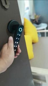 a hand holding a remote control on a counter at 365house in Ban Phlu Yai