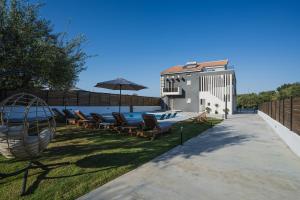 a backyard with a pool and chairs and an umbrella at G-Ammos 5 Star Villa by elite in Tragaki