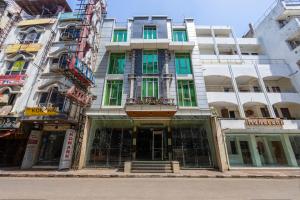 a tall white building with green windows on a street at Hotel Aura - 05 Mins from New Delhi Railway Station & Connaught Place in New Delhi