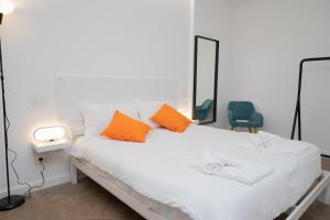 a white bed with orange pillows and a blue chair at Seven Thousand Apartment in Brescia