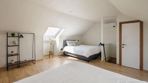 a white bedroom with a bed and a window at Huisje aan de Schelde in Spiere
