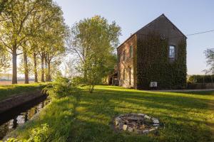 an old house with a fire pit in the yard at Huisje aan de Schelde in Spiere