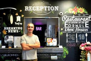 a man is standing in front of a bar at Sud Hôtel Restaurant in Bastia