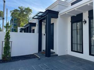a white house with a black door and a fence at La Casa Bella in Ban Nong Chaeng