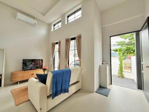 a living room with a white couch and a tv at La Casa Bella in Ban Nong Chaeng
