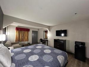 a hotel room with a bed and a flat screen tv at Speedway Inn & Suites in Griffin