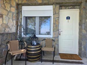 a stone house with two chairs and a door at Casa Horizont in Slankamenački Vinogradi