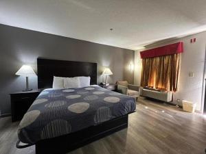 a hotel room with a bed and a living room at Speedway Inn & Suites in Griffin