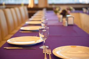 a long purple table with plates and wine glasses at My House Hotel in Samsun