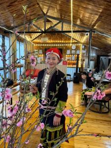 a woman is standing in a room with flowers at Sapawine Homestay in Sapa