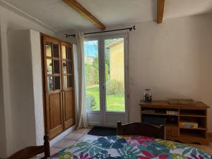 a bedroom with a bed and a sliding glass door at Ma maisonnette en Cévennes in Le Vigan