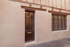 a building with a black door and two windows at Maison POHESY in Figeac