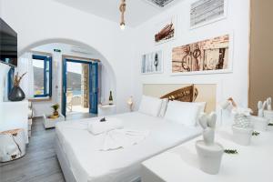 a white room with a large white bed and tables at Kaerati Apartments in Katapola