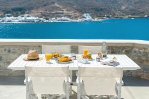 a white table with food and a view of the ocean at Kaerati Apartments in Katapola