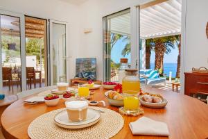a wooden table with breakfast foods and drinks on it at Villa Gabbiano - Scopello-Villas in Scopello