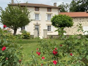 an old house with red roses in front of it at La maison d'eugénie in Jourgnac