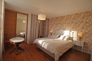 a bedroom with a bed and a table and a mirror at La maison d'eugénie in Jourgnac