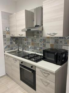 a kitchen with a stove and a microwave at SeaYouSoverato Apartment in Soverato Marina