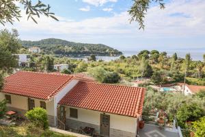 a house with an orange roof with a view of the water at Studios Villa Eleni in Skiathos